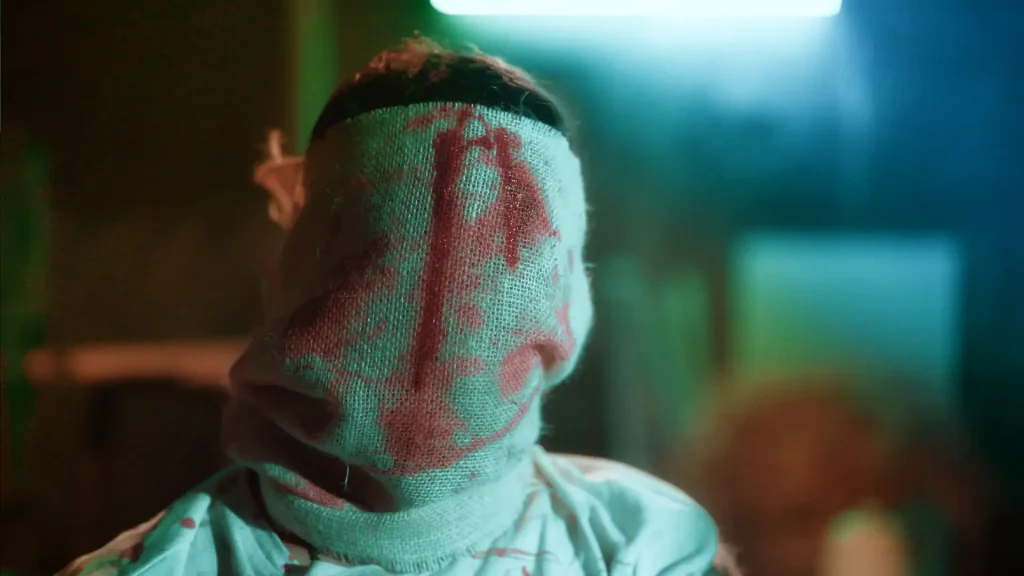 An injured man with bloodstained bandages covering his head and face in the Bangla Full Natok Sei Ami Nei Ami.